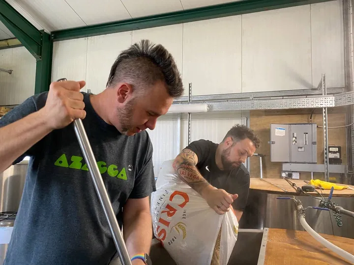 Ken from Mysterious Brewing stirring the mash while Mark tips in a sack of malt